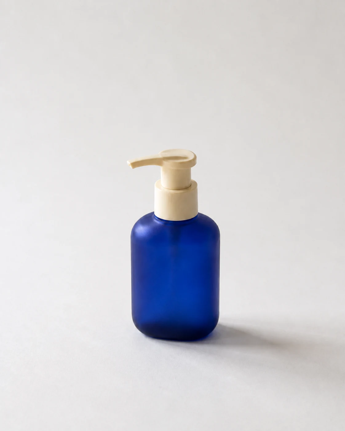 Blue pump bottle on a clean neutral background after light exposure and color correction.