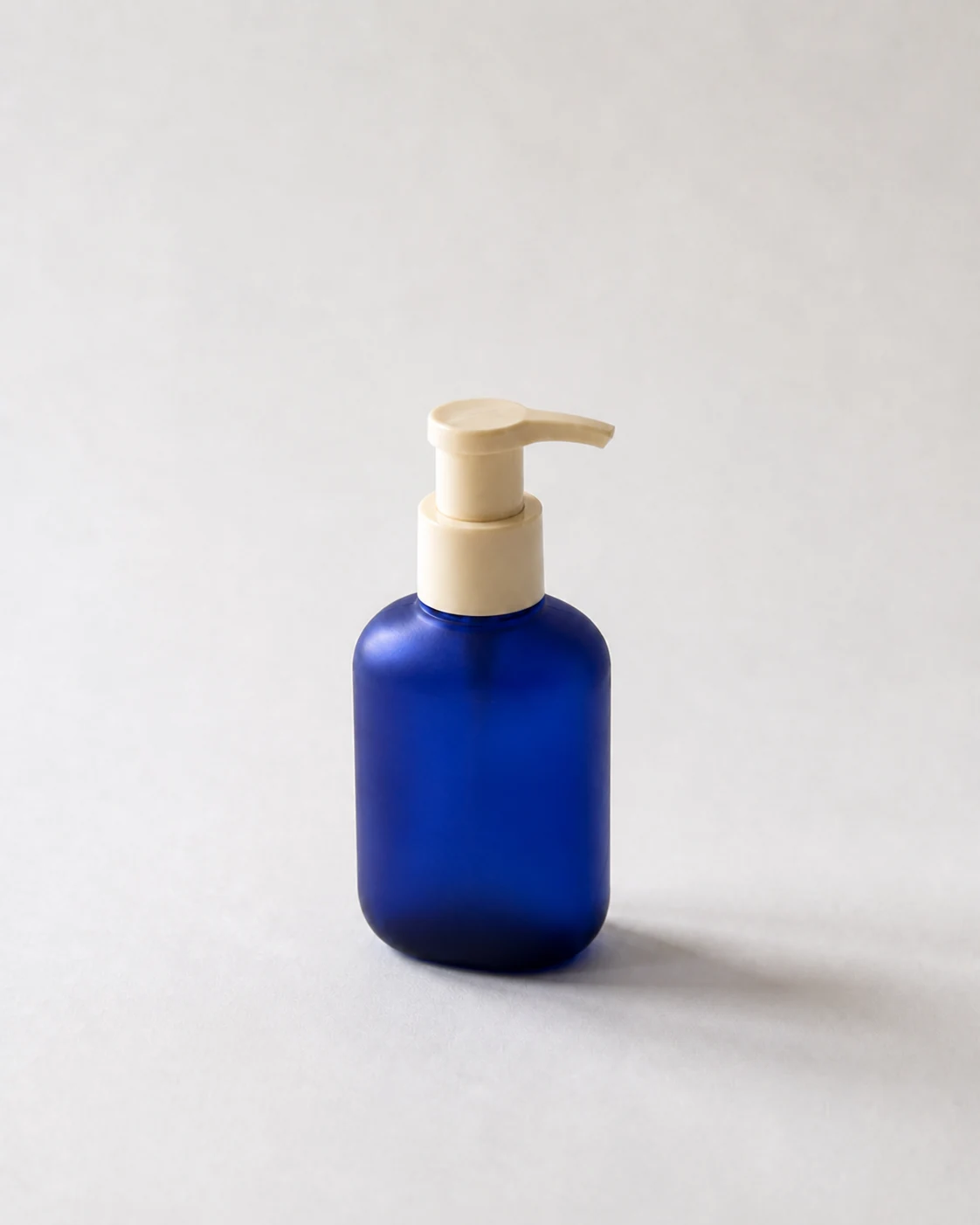 Supporting side view of a blue pump bottle on a neutral background.