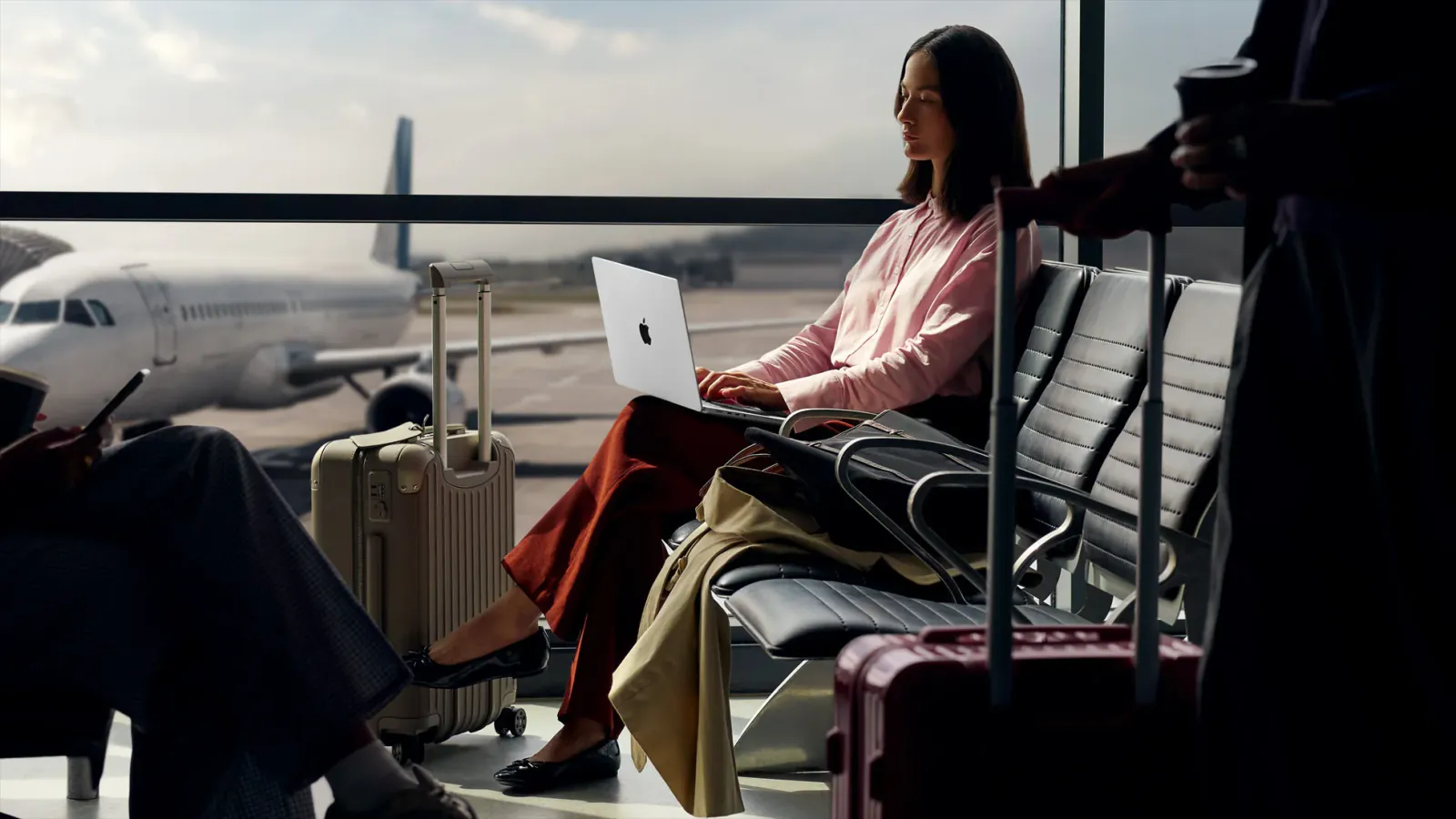 A traveler uses a silver 14-inch Apple MacBook Pro while waiting at an airport.