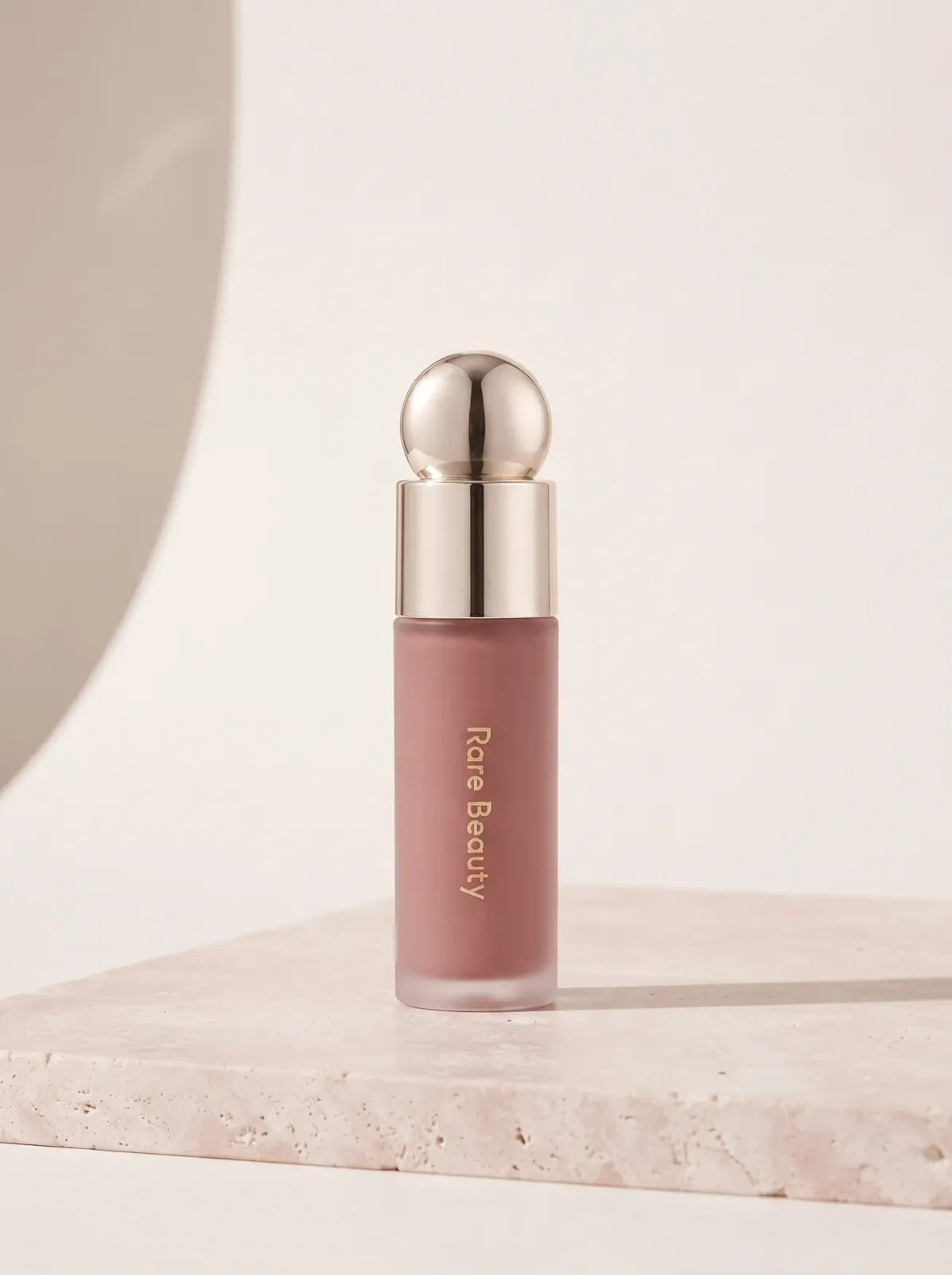 The same liquid blush bottle in a pale soft-minimal beauty composition.